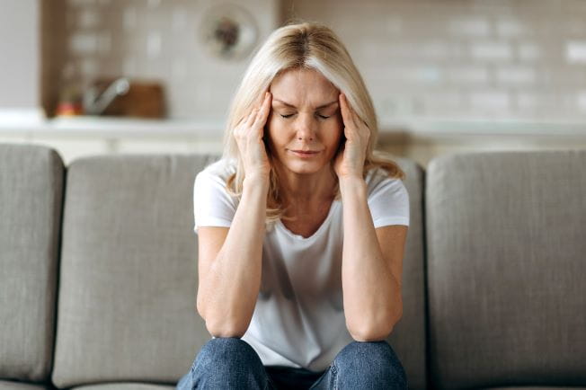 Woman holding her temples while experiencing a headache